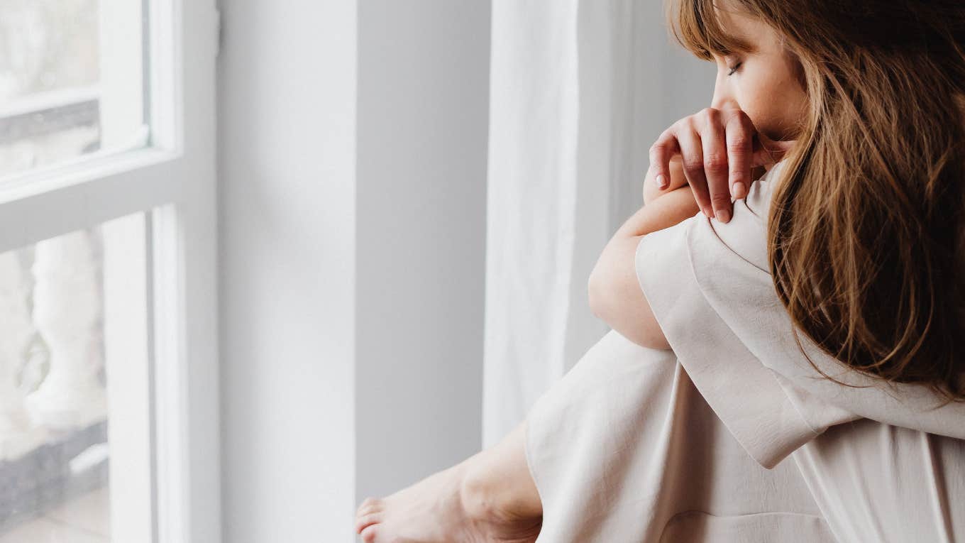 Why It Hurts So Freaking Much To Get Over An Ex, According To Research Woman sitting with her grief after a breakup