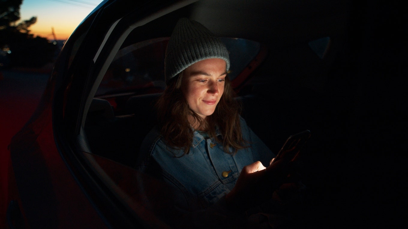 A woman is in the back of a car at night.