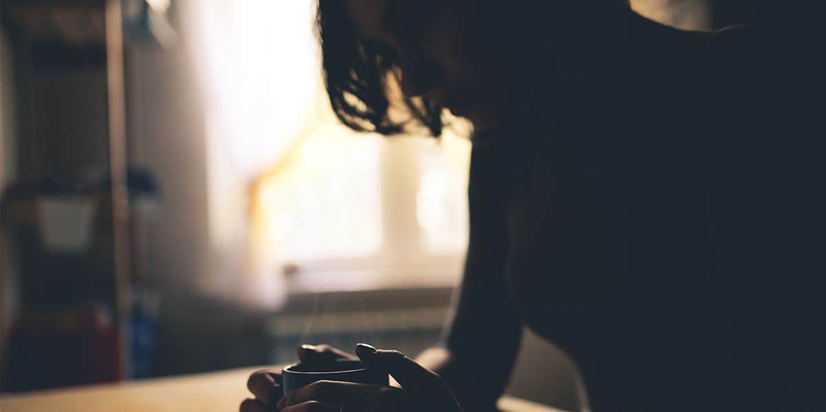 woman sitting in the dark with cup of coffee