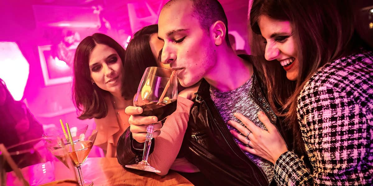 man surrounded by women in a bar