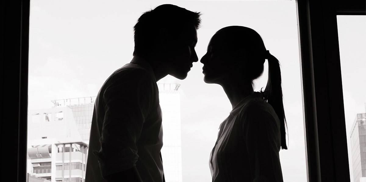 black and white silhouette of man and woman in front of a window