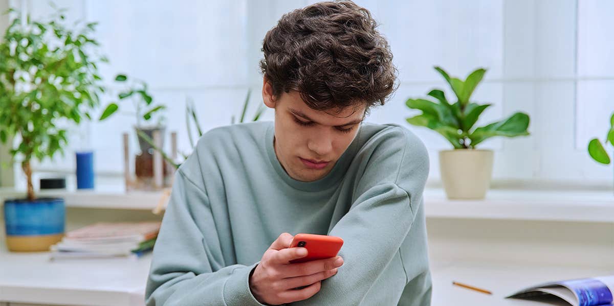 teen guy texting in bedroom