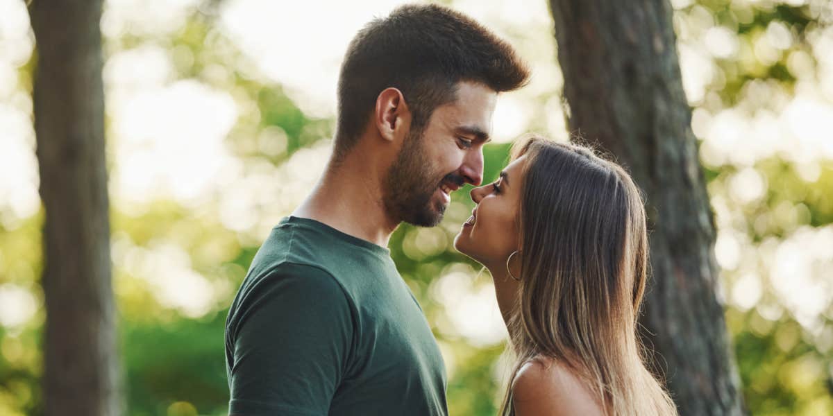 brunette couples about to kiss in the woods, smiling