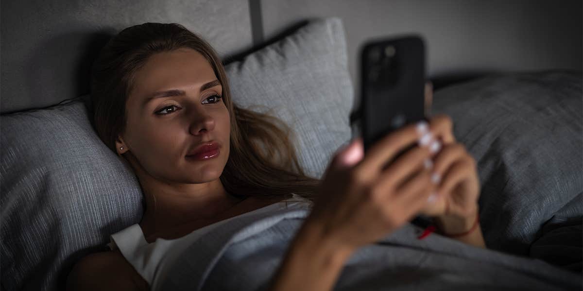 girl in bed looking at phone at night