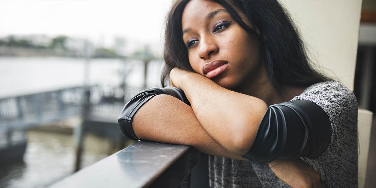 woman looking forlorn leaning on balcony