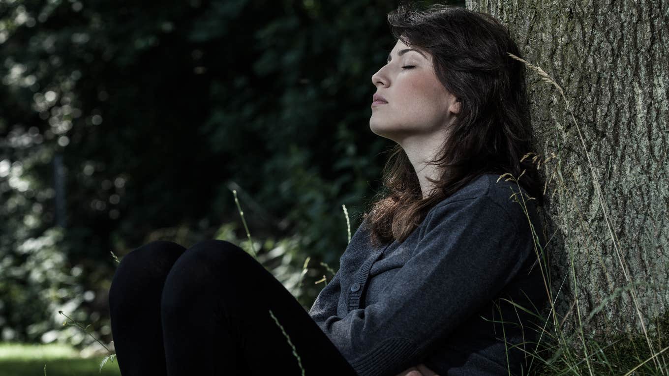 grieving woman sitting against tree