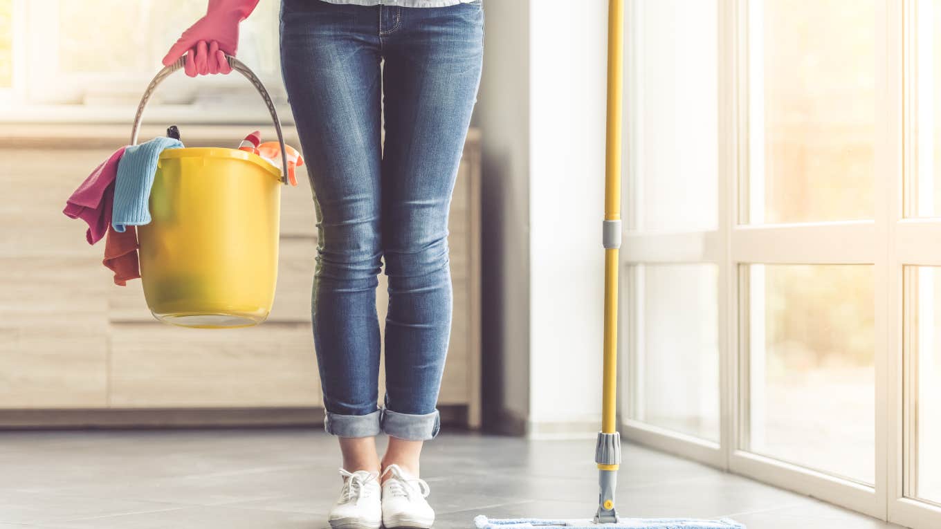 woman holding a mop and a bucket of cleaning supplies