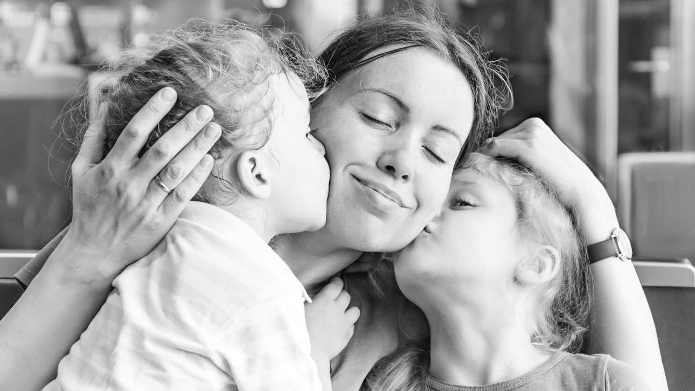 two daughters kissing their mom on the cheeks