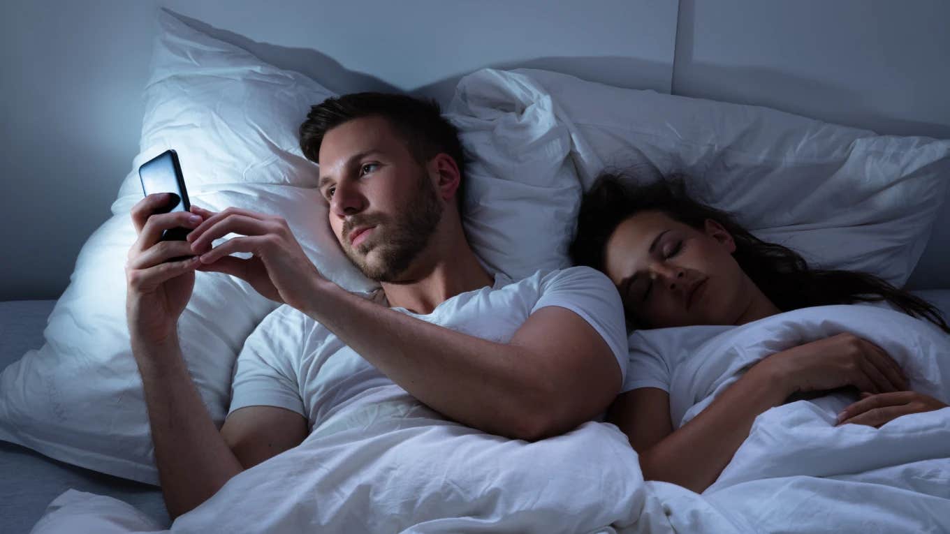 husband on the phone with his co-worker in bed while next to sleeping wife