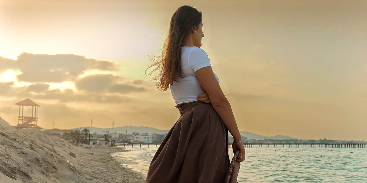 If You Don't Drop These 10 Mindsets, You'll Never Find Love girl standing alone watching ocean