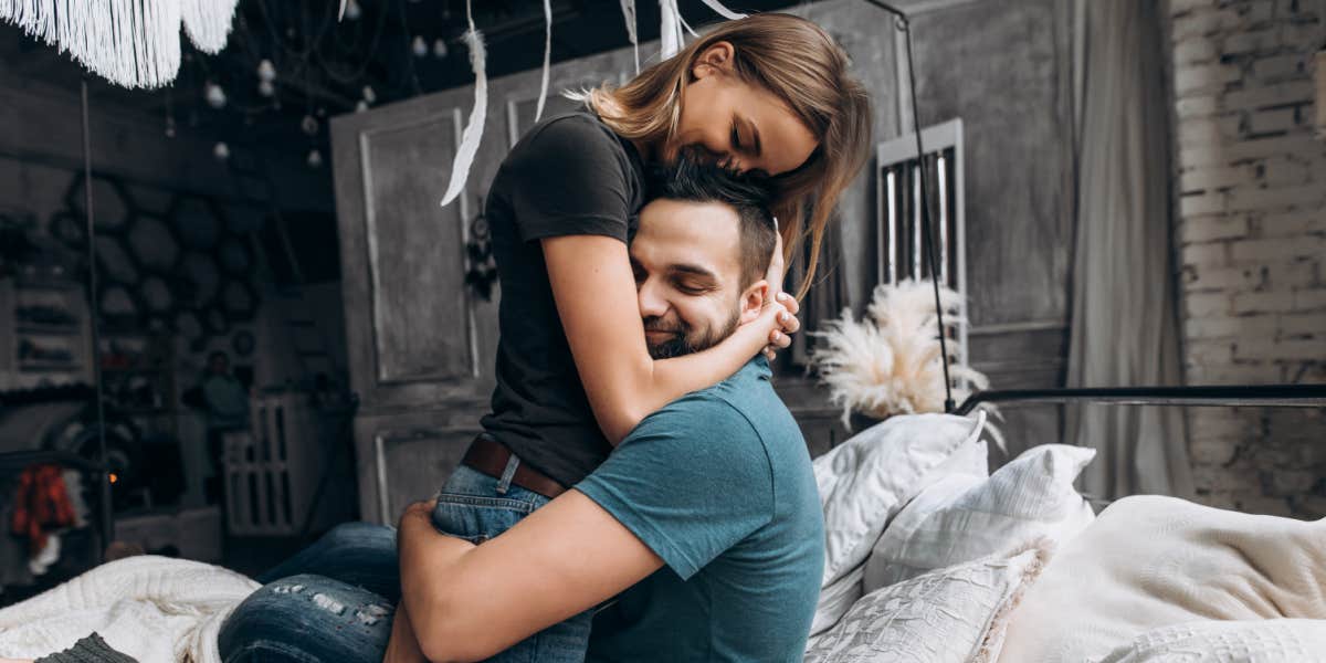 couple cuddling in a sweet way, she hugs his head and he hugs her waist