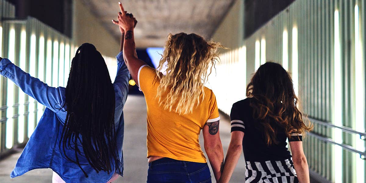 group of three teenaged girls walking down hallway together