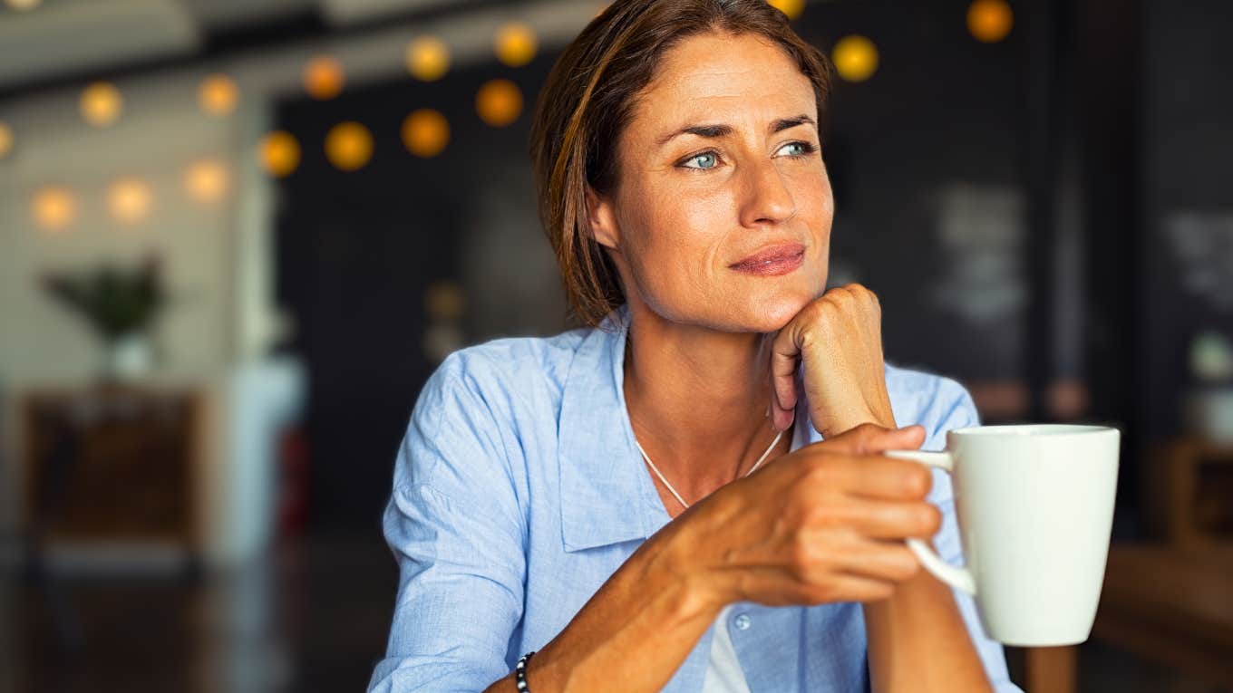 thoughtful woman holding coffee mug looking upward