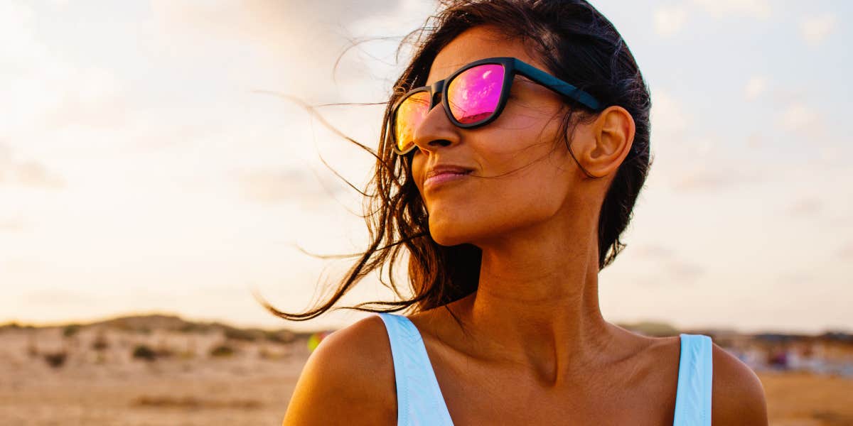 South Asian woman looks sideways in the desert, wearing sunglasses