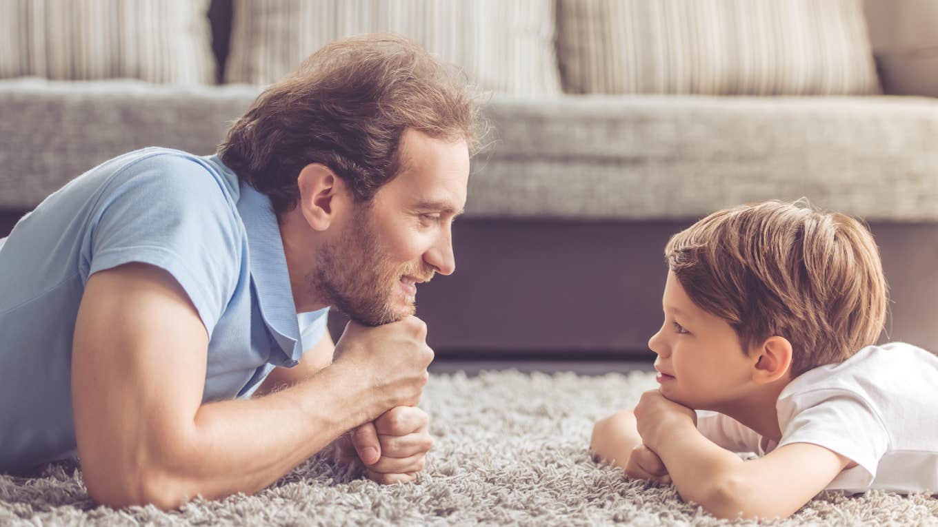 father and son laying on the floor looking at each other