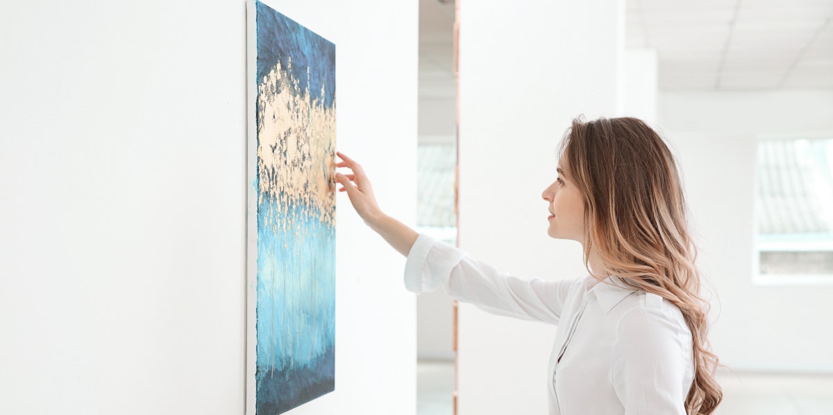 woman looking at painting hanging on the wall