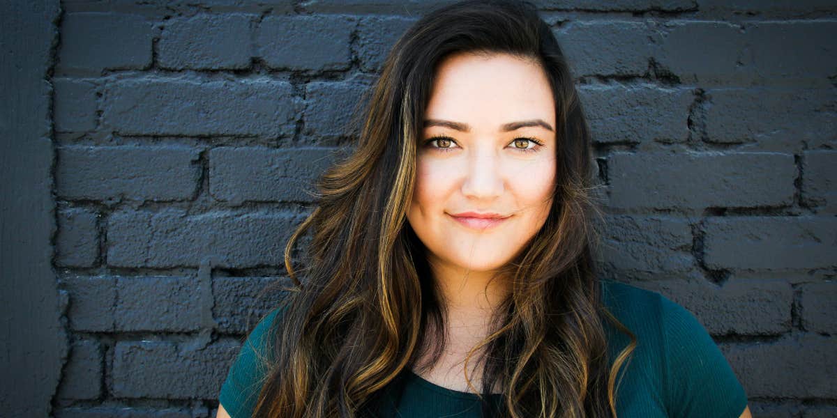 Woman Refuses To Drop Ex-Husband's Last Name After He & His Fiancé Claim It's 'Weird' She Still Has It Woman in front of black wall