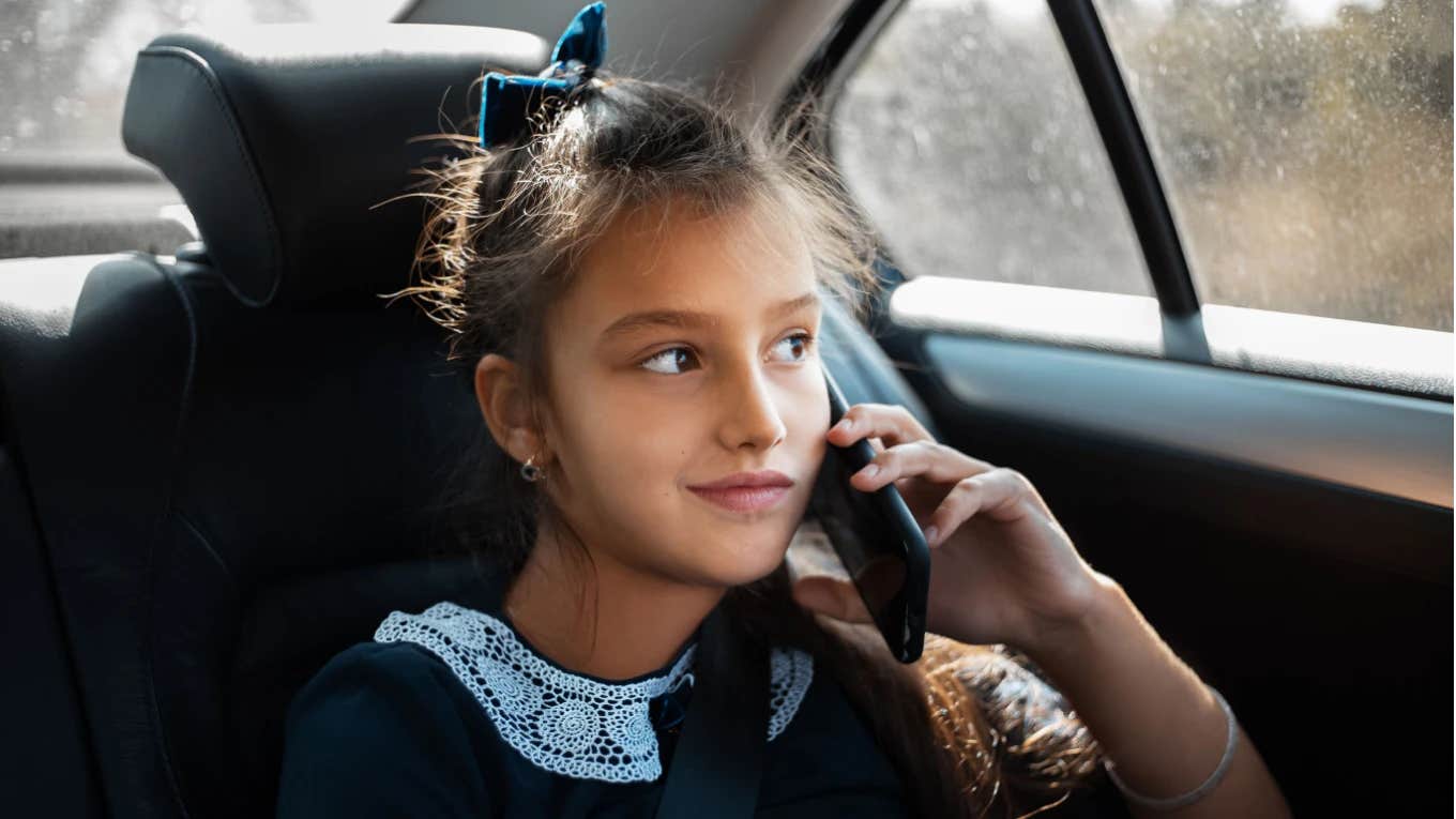 young teen rides in the backseat of an uber while on the phone 