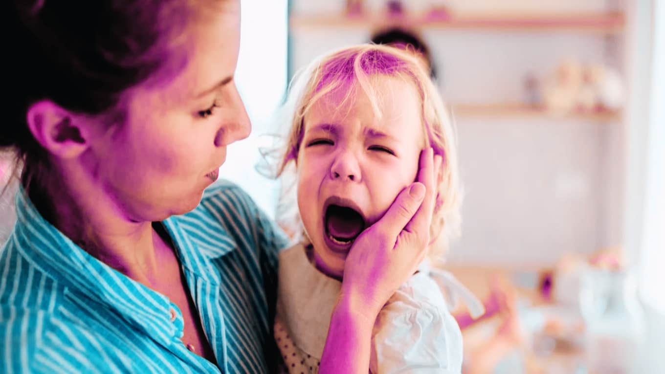 woman holding screaming child's face
