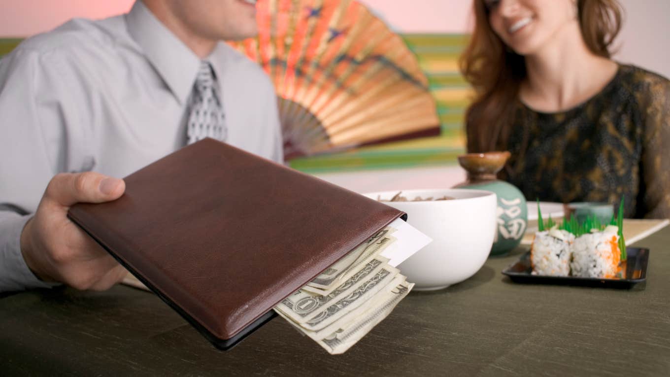Couple paying with cash at a restaurant.