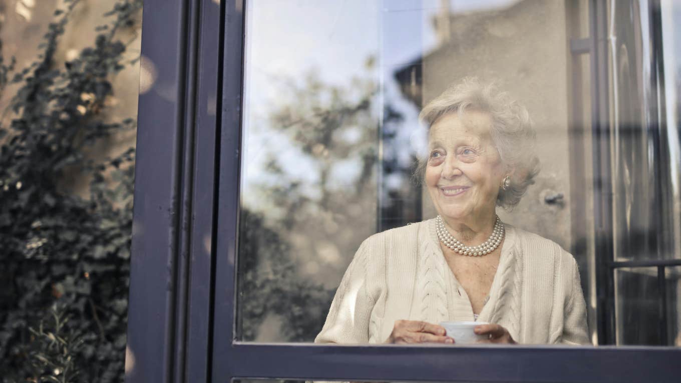elderly woman inside looking out window