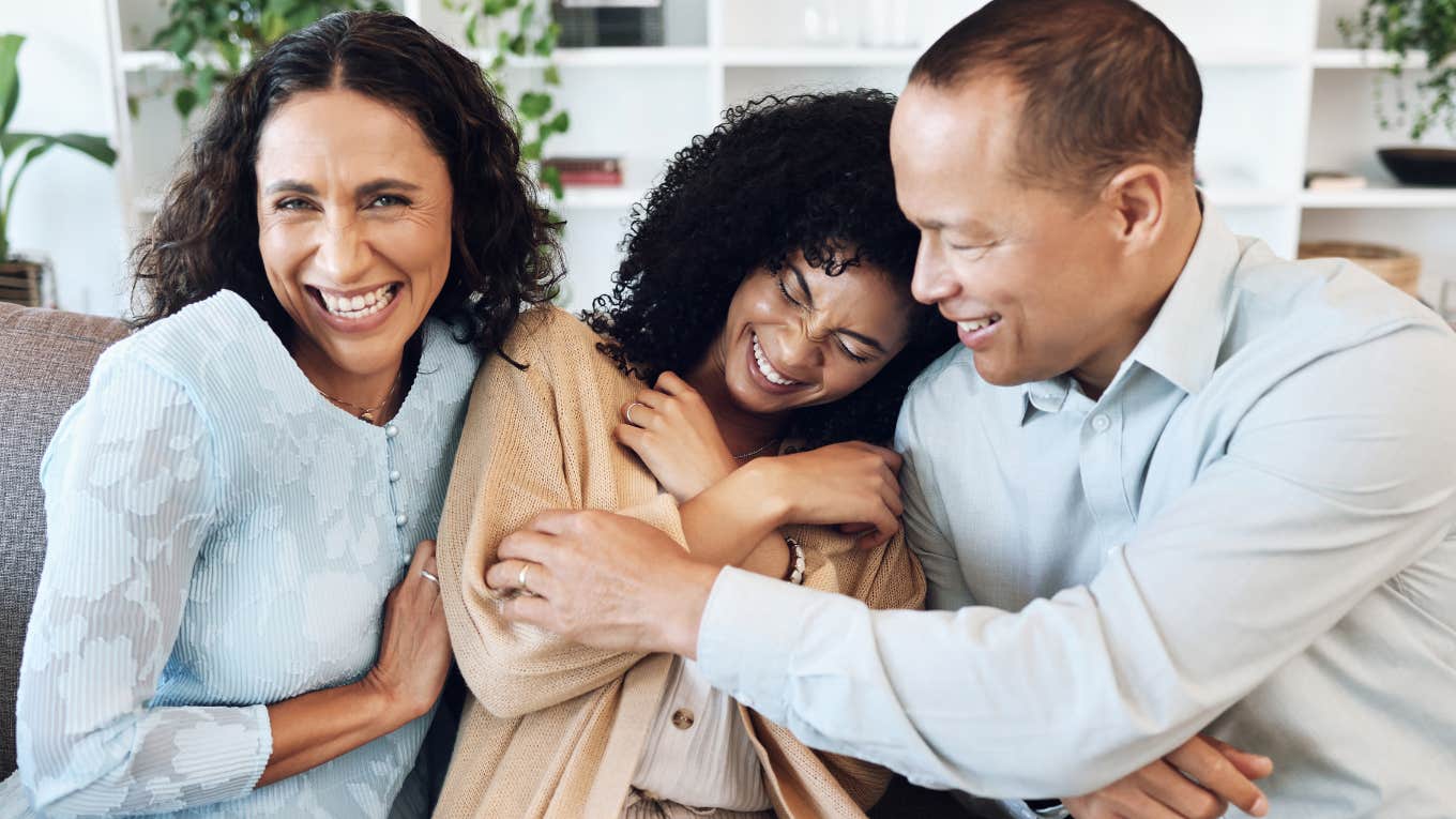 Mother and father hugging their adult daughter. 