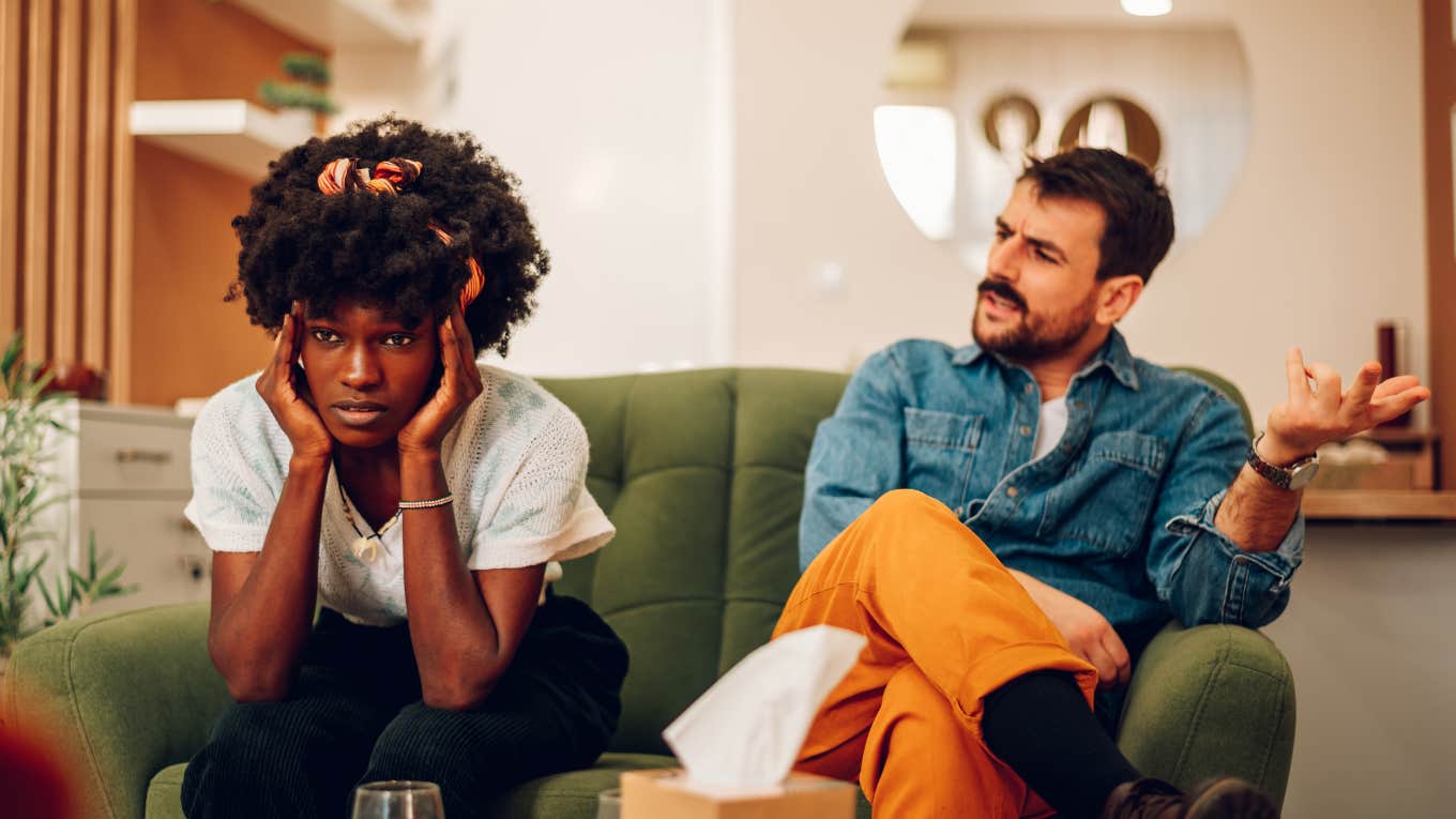 Woman Says Her New Husband Secretly Put His Last Name On Their Marriage License couple sitting on couch and upset at each other