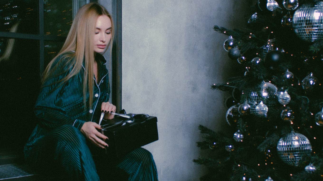 woman opening christmas gifts alone