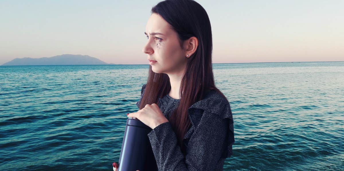 Woman holding ashes, ocean view