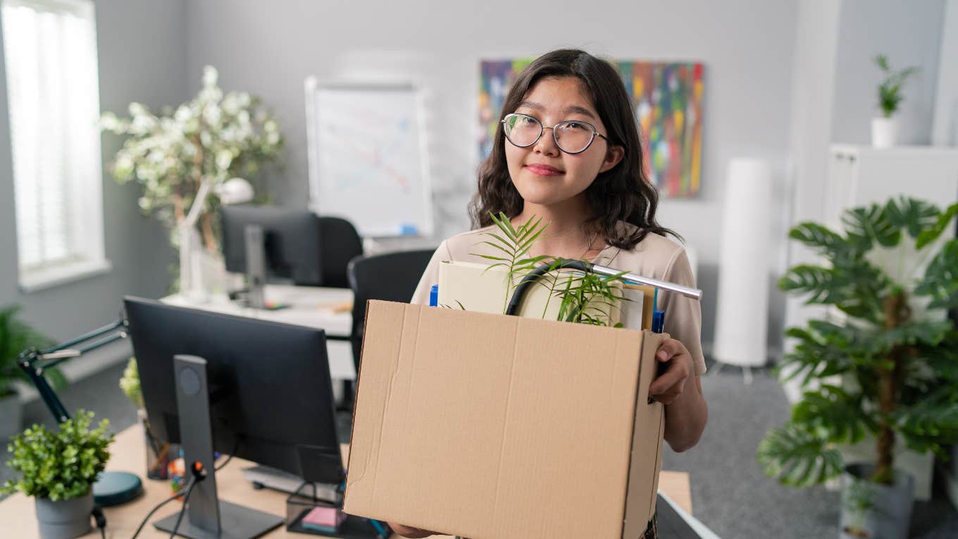 woman carrying box of belongings out of office