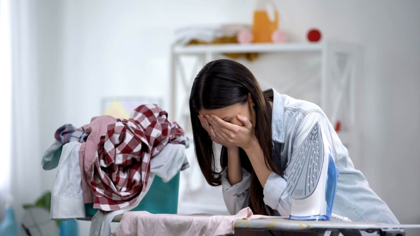 woman crying into her hands surrounded by laundry