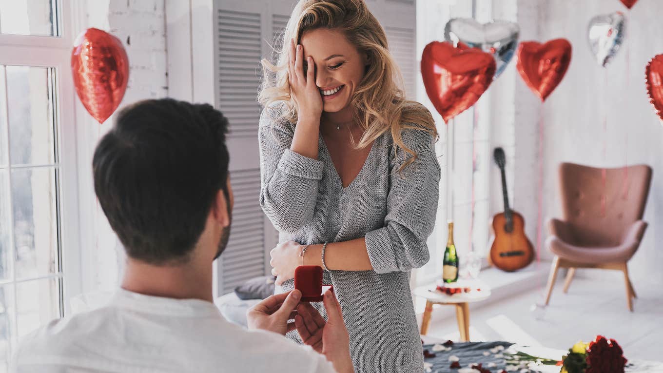 man holding engagement ring while making proposal to his happy girlfriend