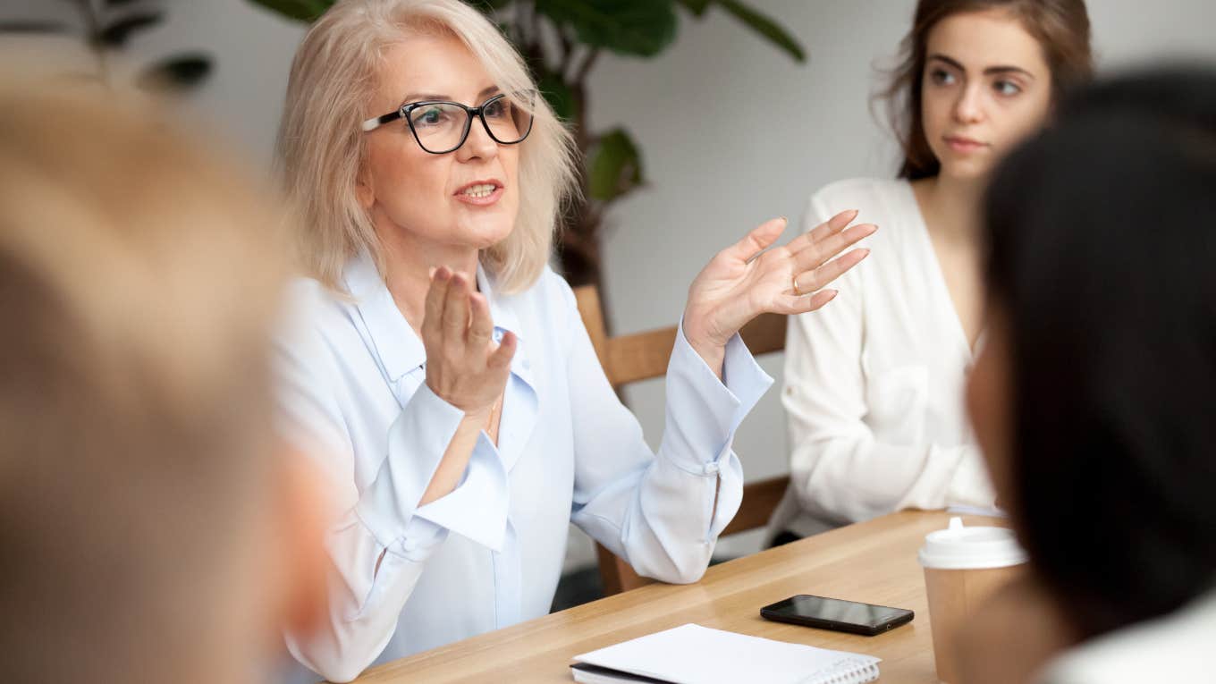 senior woman in glasses teaching audience at training seminar