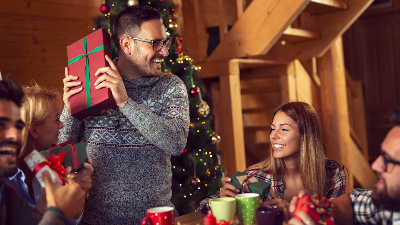 friends sitting next to a nicely decorated Christmas tree and exchanging Christmas presents and having fun