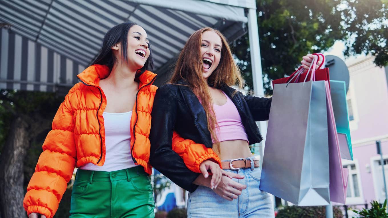 two women smiling while holding shopping bags