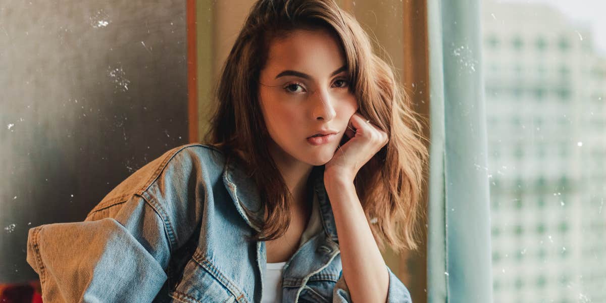 Woman facing camera beside window