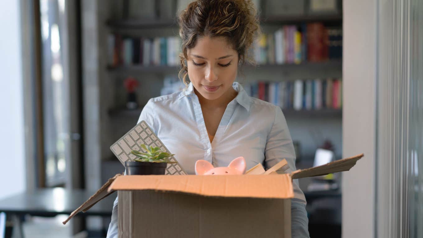 sad woman carrying box of office items after being fired