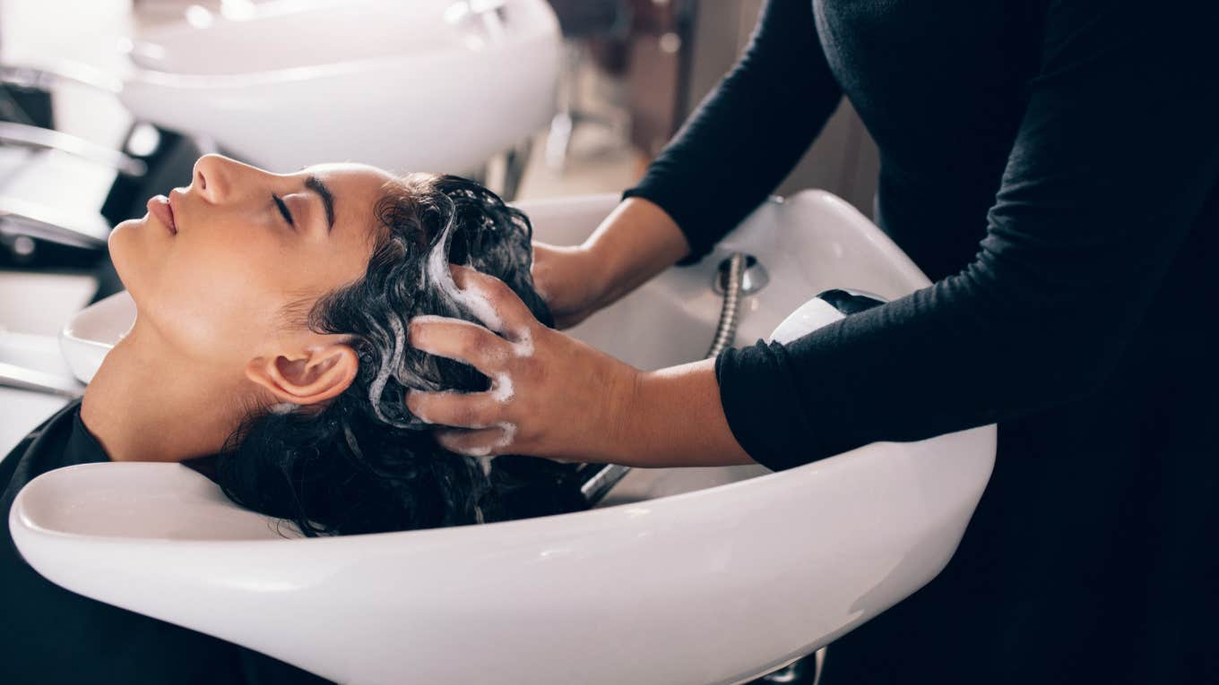 hair salon employee scrubs shampoo into woman's hair