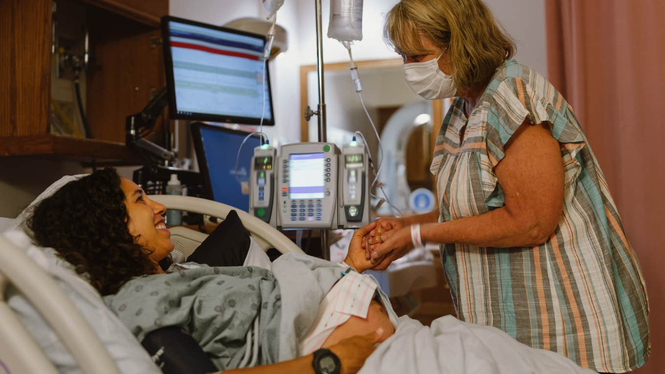 pregnant woman in labor holding another woman's hand while in hospital delivery room