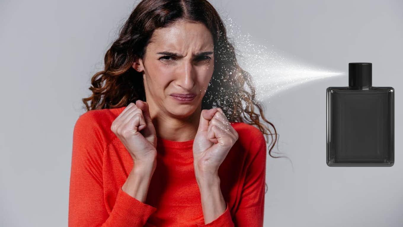 woman in red sweater grimacing in spray of perfume