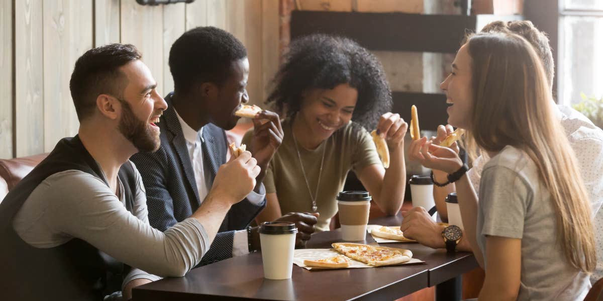 Group of friends laughing while eating lunch together