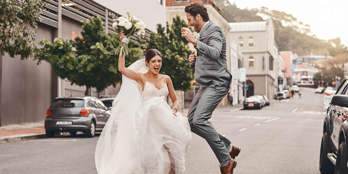 Bride and groom jumping in the street