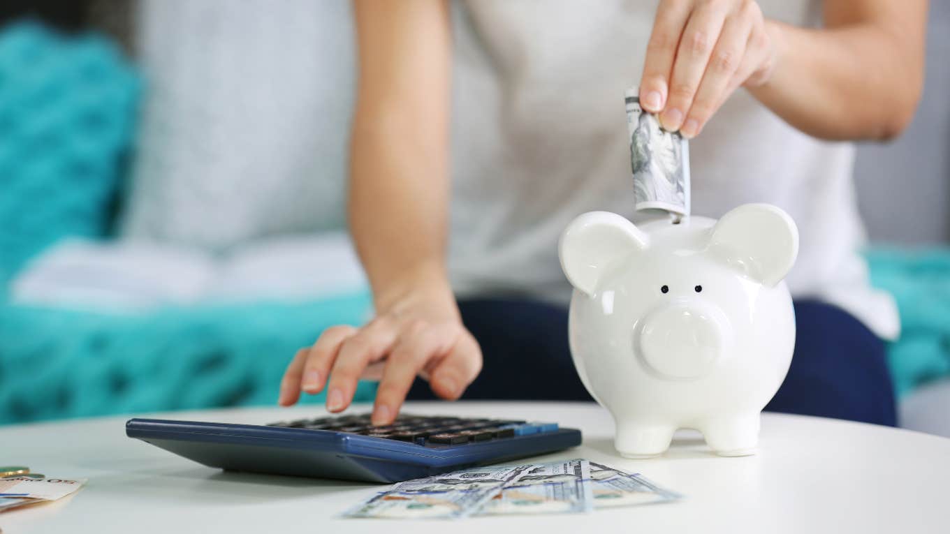woman budgeting with calculator and putting money in piggy bank