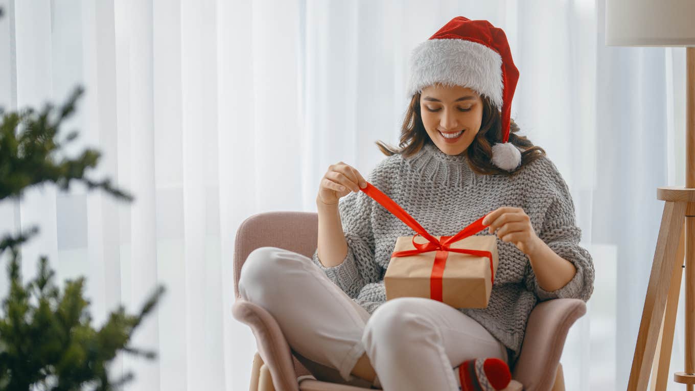 woman wearing santa hat opening christmas gift