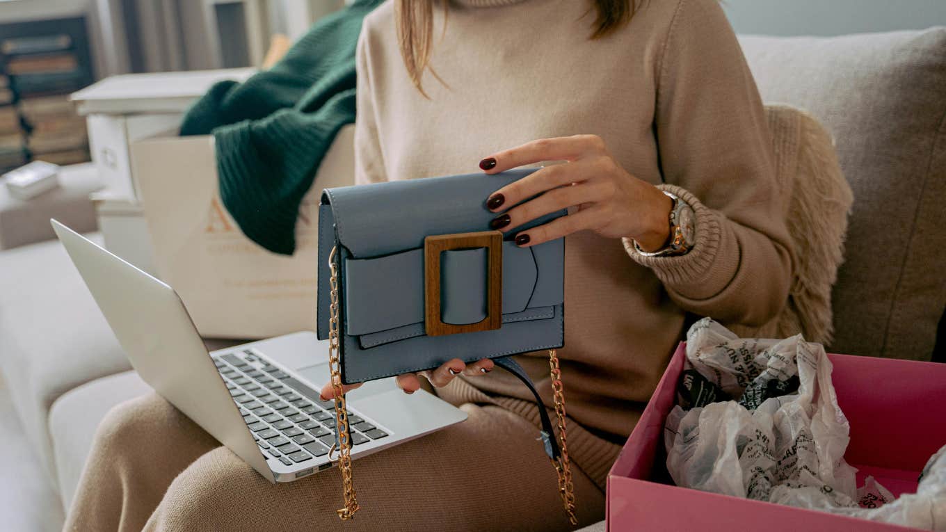 woman sitting on couch with laptop and unboxing new bag