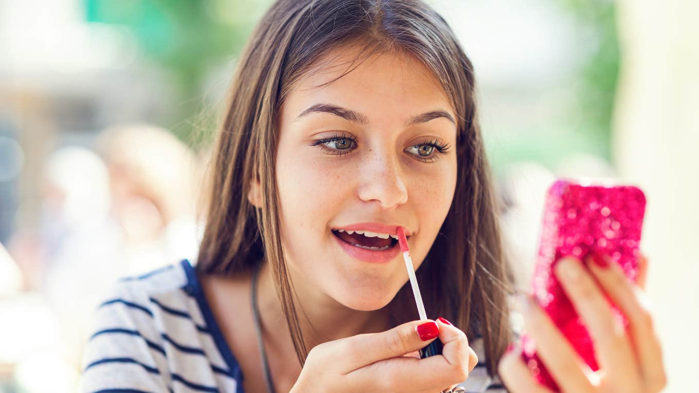 tween girl putting on lip gloss