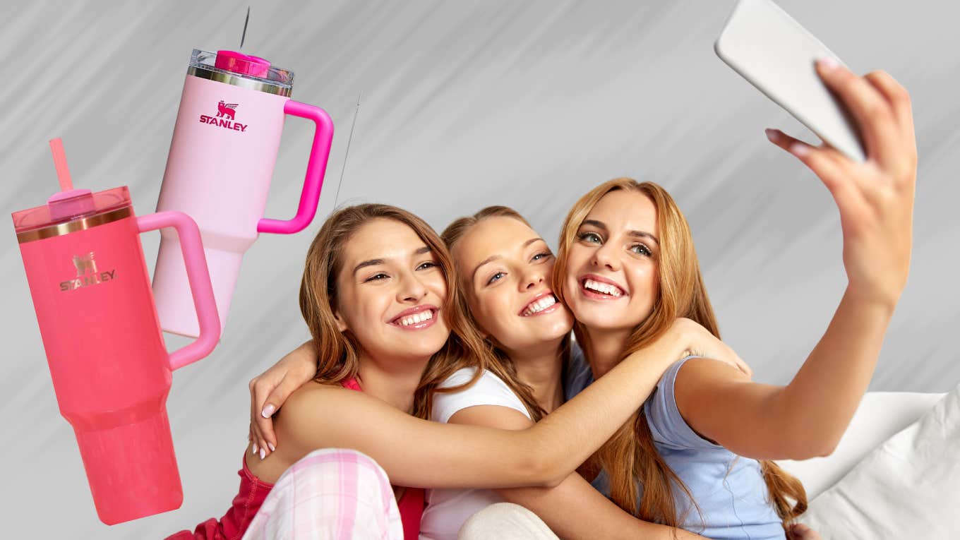 Teenage girls taking a selfie with pink Stanley cups. 