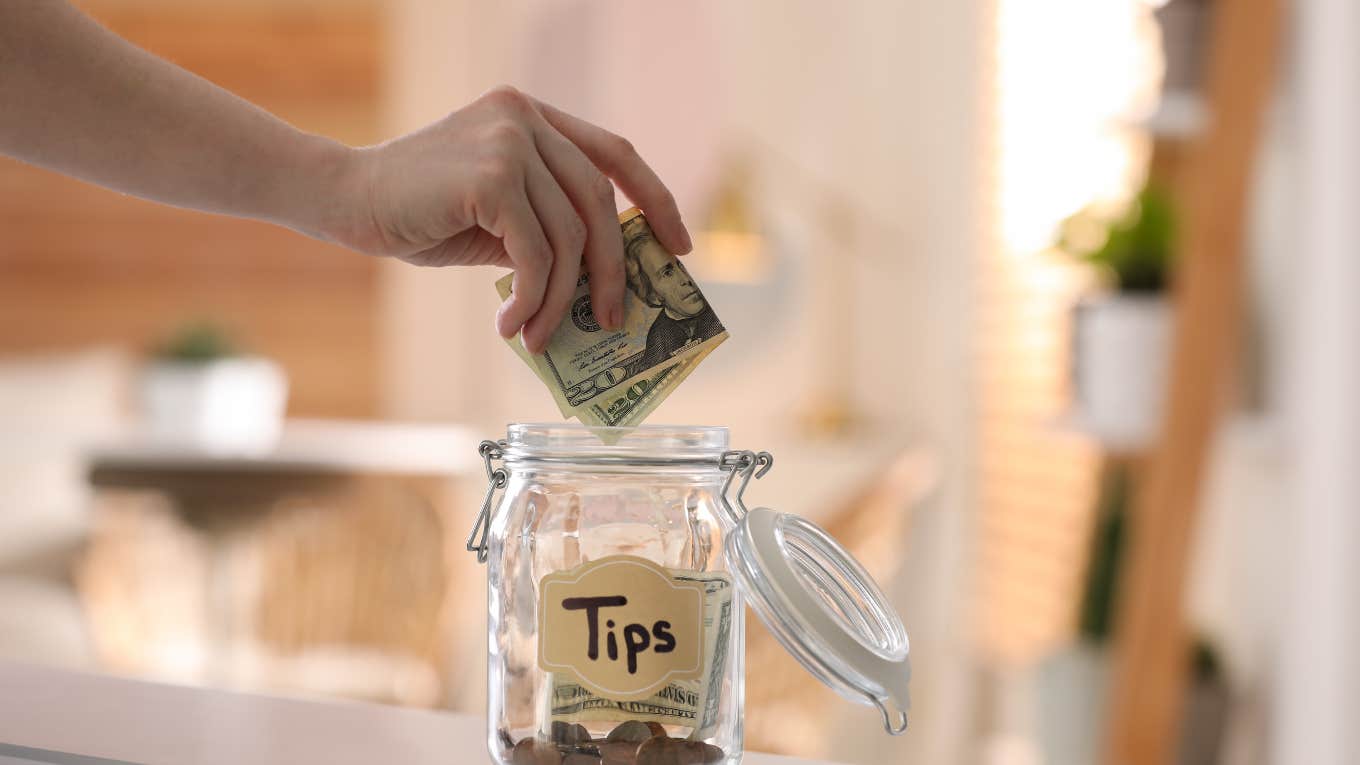 hand putting money in a tip jar