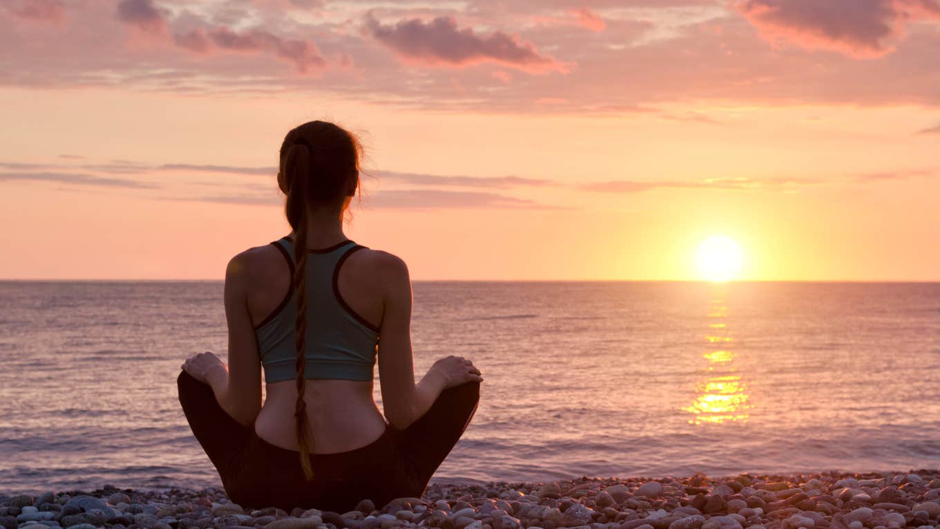 woman practicing visualization on beach at sunrise