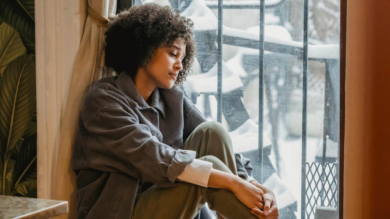 sad woman sitting by window 